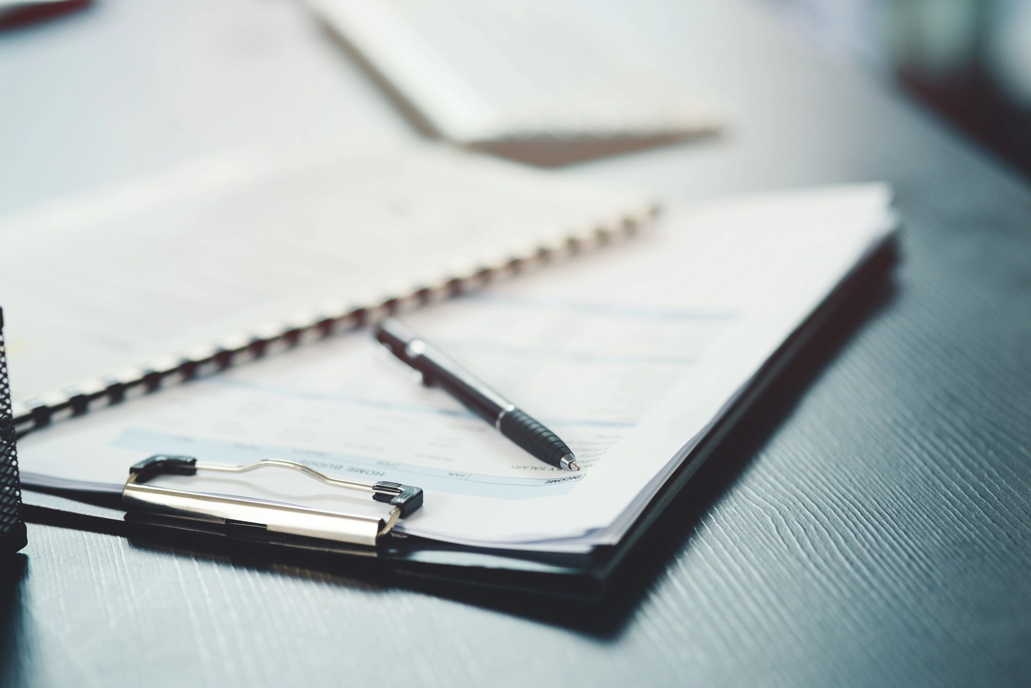 Notebook and pen on a desk representing organized diligence tracking